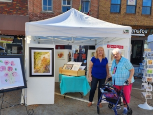 Artists Jeanette Carson and Jo Myers-Walker in front of their booth at the 2023 Octagon Art Festival in downtown Ames, Iowa